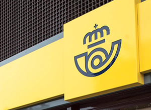 Rótulo con el logotipo de CORREOS en el exterior de una oficina.