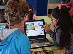 Un niño y una niña, estudiando con un ordenador.