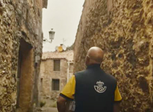 Cartero de Correos llevando un paquete.